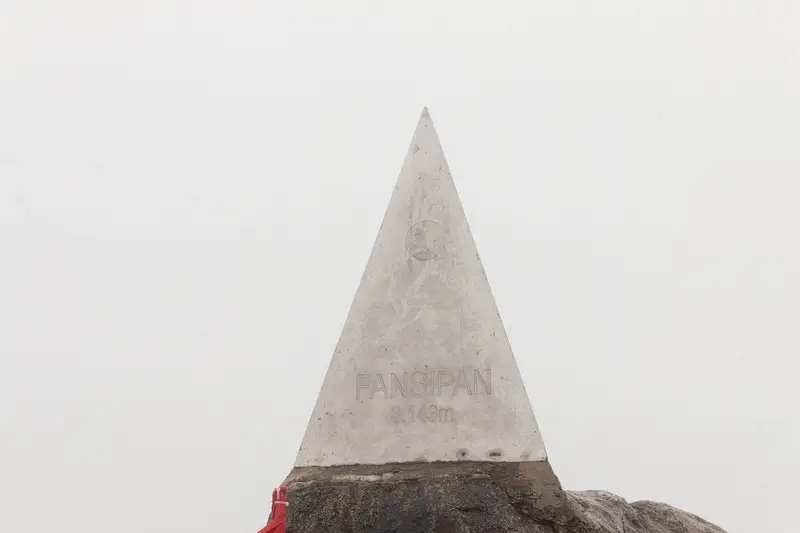 The pyramid summit marker on Fansipan against a white, foggy sky
